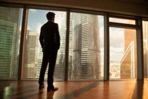 une photo d’un homme regardant par une fenêtre à gratte-ciel