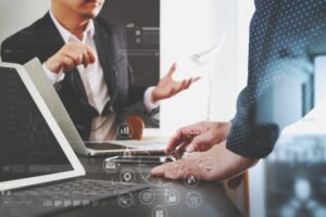 une photo de deux personnes parlant avec un ordinateur portable