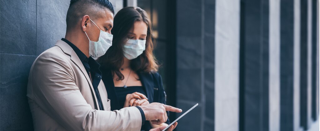 Two business people meeting outside wearing face masks