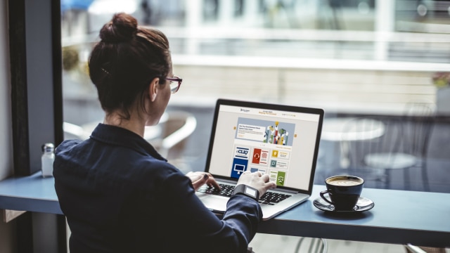 Woman typing on laptop at counter with coffee