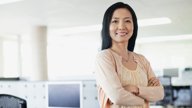 Smiling woman standing in office with her arms folded