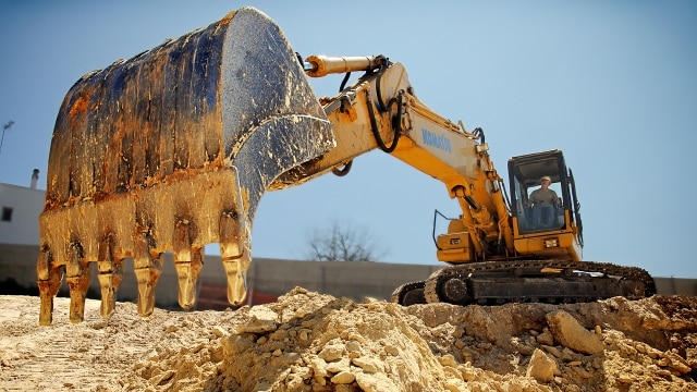 Digger on construction site pulling at soil