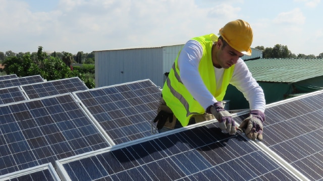 Man with hardhat and high visibility vest installing solar panels