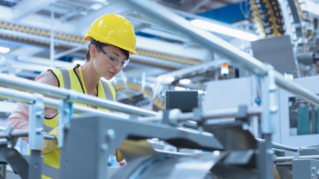 Woman with hardhat and safety glasses in a manufacturing facility