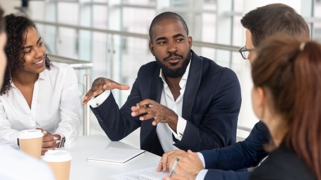 Group of professionals in business attire sitting at table and having a conversation