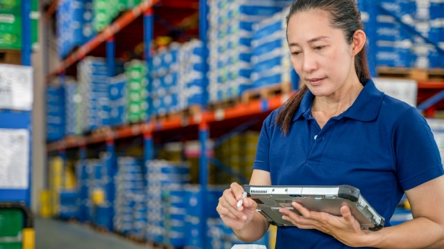 Woman standing in warehouse looking at electronic tablet