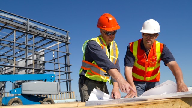 Two men on construction site looking at plans