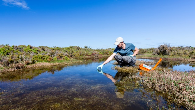 Man collecting water sample from river