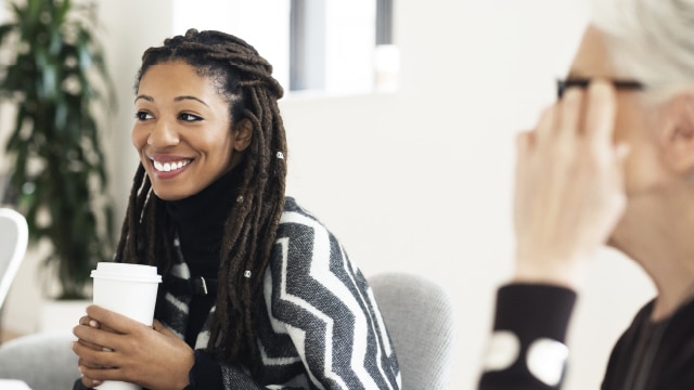 Woman holding a cup of coffee while in a meeting