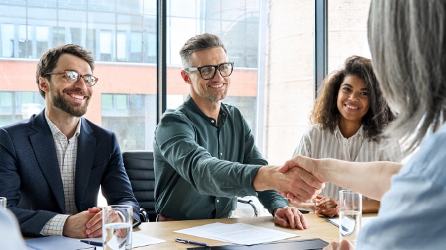 Business people shaking hands while sitting down and smiling