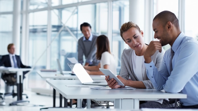 Business people sitting at a table and looking at an electronic tablet