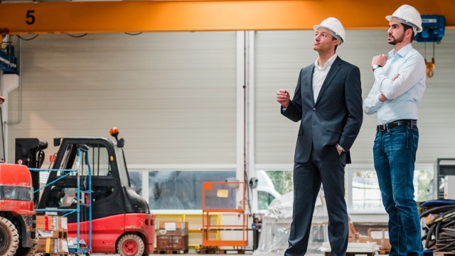 Two men in hardhats standing in a warehouse