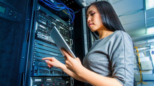 Woman standing with electronic tablet and pushing buttons on a server