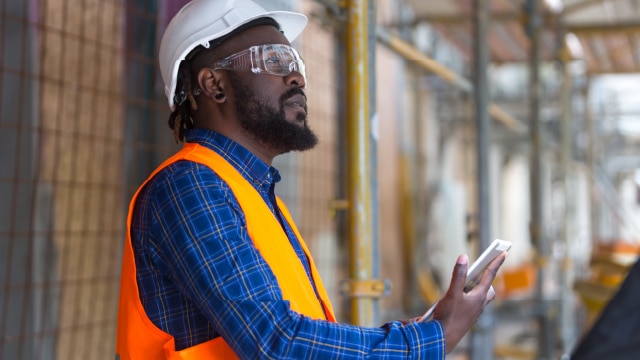 Man on construction site looking at electronic tablet