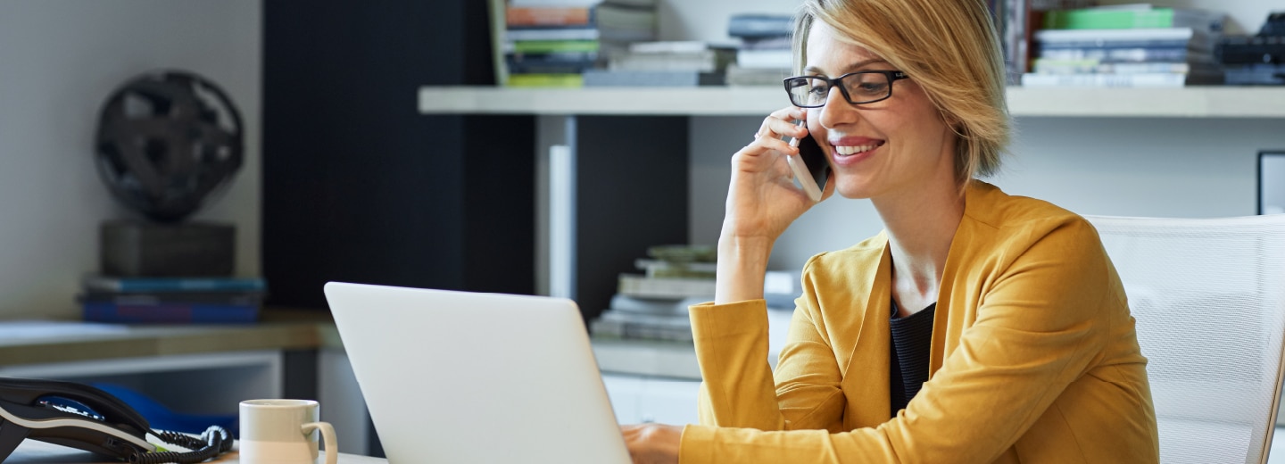 Woman talking on the phone while looking at laptop