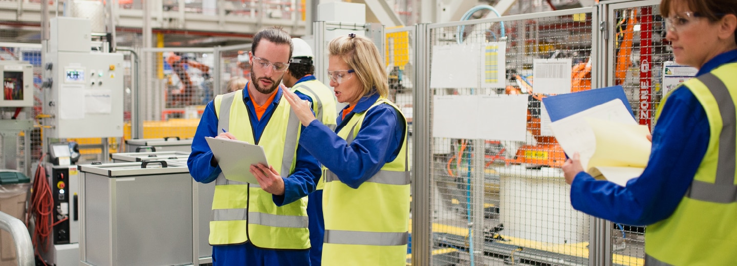 People in manufacturing facility looking at paper and discussing