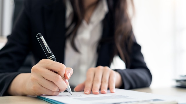 Person reading and signing a contract