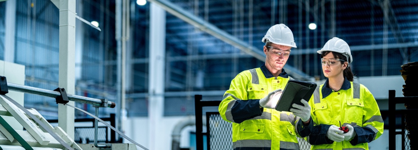 People in a manufacturing facility holding a tablet device